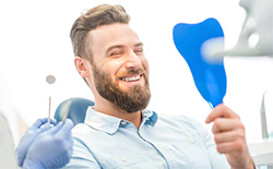 Man smiling in mirror at dentist