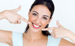 Young woman pointing to flawless smile