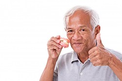 Man holding dentures in Texarkana giving thumbs up