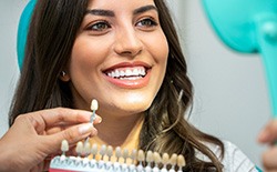 A woman using a tooth shade chart