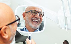 Man in glasses smiling in reflection in treatment chair