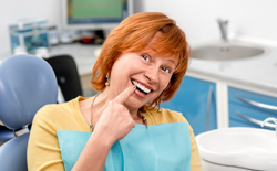 Senior woman pointing toward healthy smile