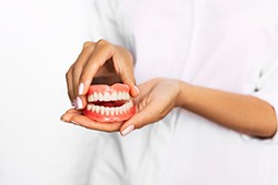 Texarkana dentist holding full set of dentures 