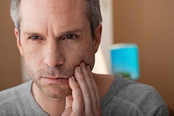 Man with tooth pain standing and looking concerned