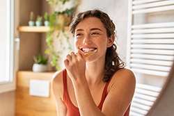 Woman standing in bathroom brushing her teeth