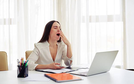 Tired woman yawning at her desk