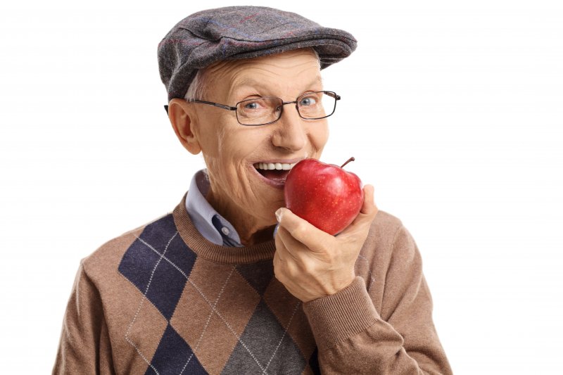 older man smiling eating apple