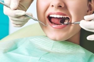 a woman getting her infected tooth examined for a possible root canal therapy