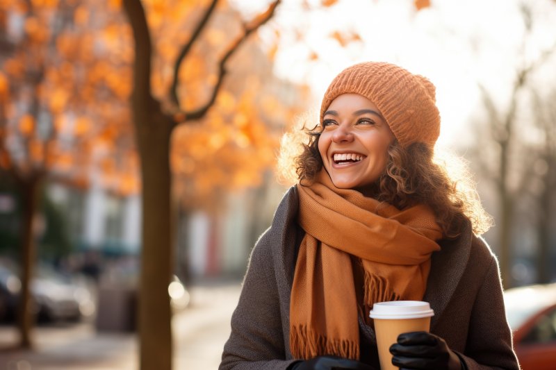 a woman smiling while holding a cup of coffee