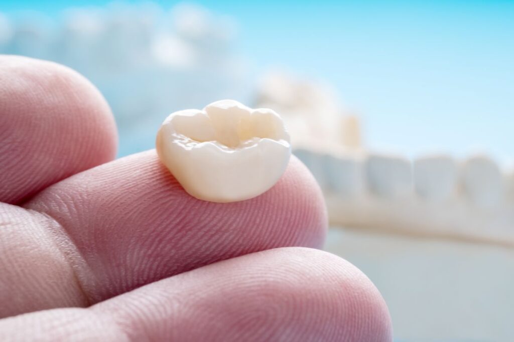 A finger holding a dental crown